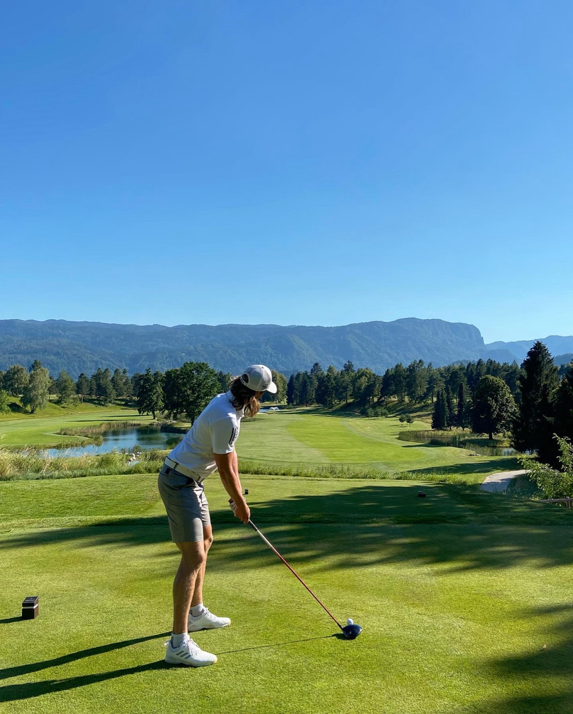 Aaron Leitmannstetter teeing off on a stunning mountain golf course